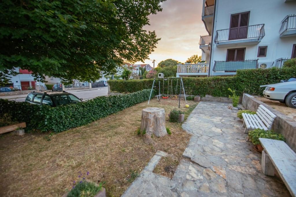 Vrt pansiona s dječjim igralištem i kamenom stazom u zalazak sunca